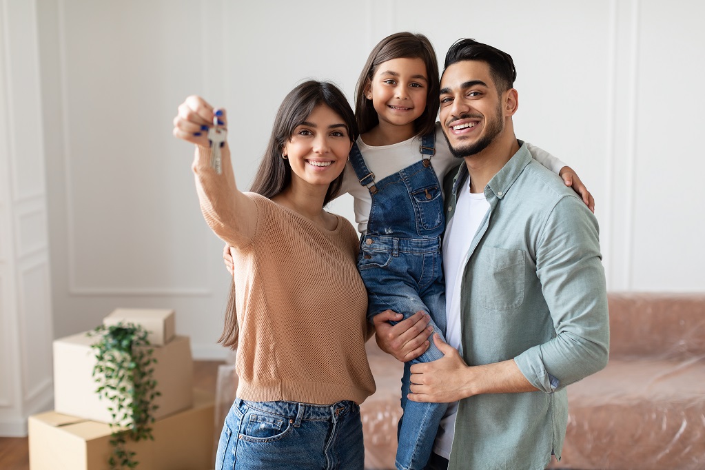 Happy young family showing keys of their apartment Portrait Of Happy Young Family Showing Key, Cheerful Parents Hugging Little Kid, Holding Daughter On Hands