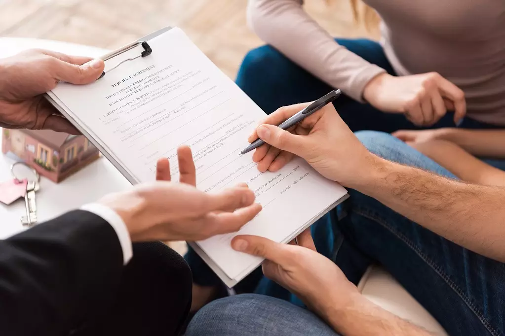 Close up of man signing agreement, family buying new apartment in real estate agency